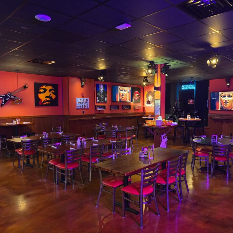 Interior of Rock N Roll Meatballs bar-&-grill with red walls, rock-themed art, and red-seated tables.