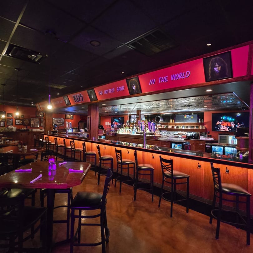 A dimly lit bar and dining area with rock and roll themed decor and purple lighting.