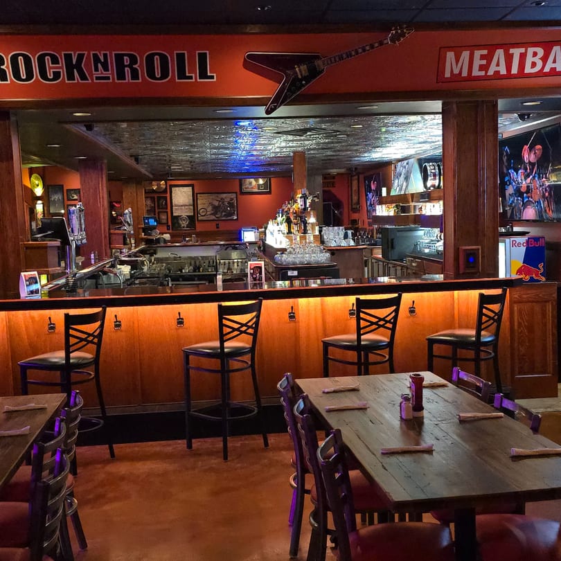 Interior of Rock N Roll Meatballs bar and grill, featuring a bar with stools and dining tables.